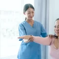 Asian Chinese female physiotherapist caregiver helping elderly woman exercise recovery osteoporosis